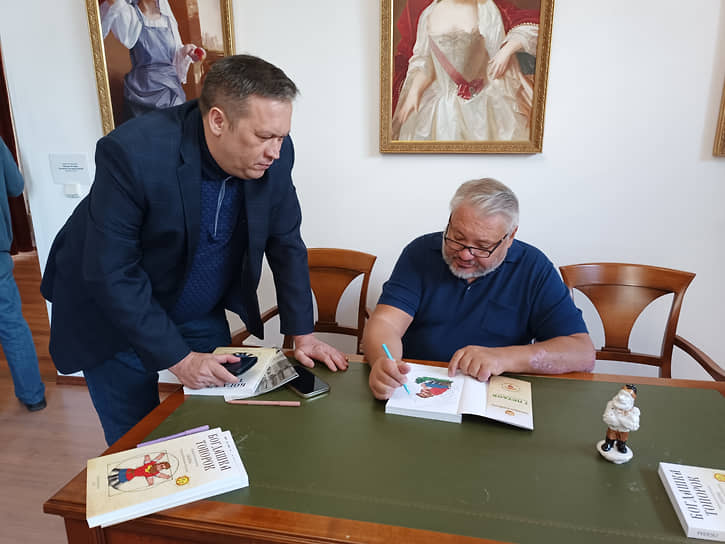 Антон Баков (справа) подписывает книгу сказов &quot;Богдашка Топорок&quot; для главного редактора &quot;Областной газеты&quot; Александра Лакедемонского (слева)