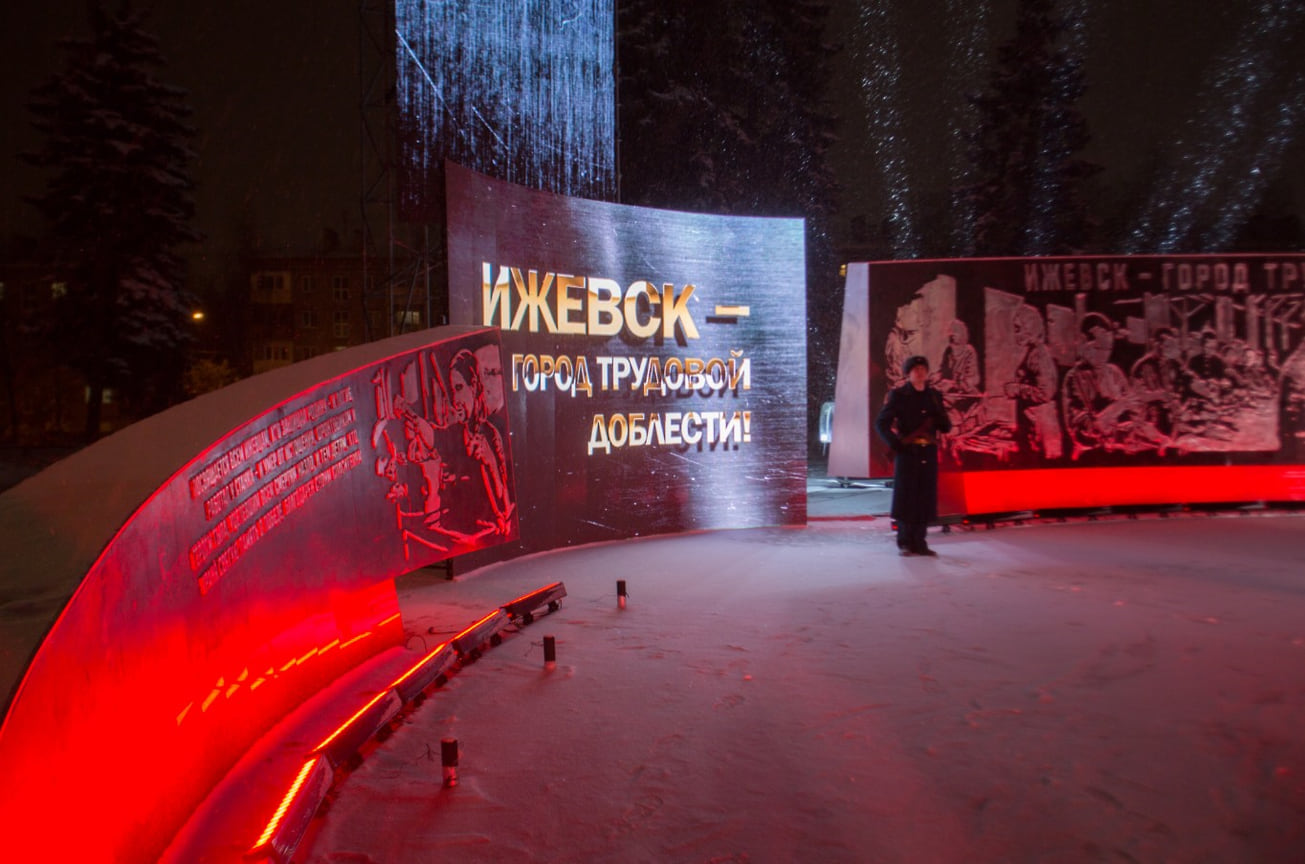 На стеле размещен герб Ижевска, а также текст указа президента России о присвоении столице Удмуртии почетного звания. Комплекс состоит из трех пилонов с металлическими барельефами, героями которых стали оружейники, металлурги, а также врачи и медсестры, работавшие в госпиталях. Подсветку памятника обеспечивают две световые опоры и 28 грунтовых прожекторов, за порядком следят видеокамеры