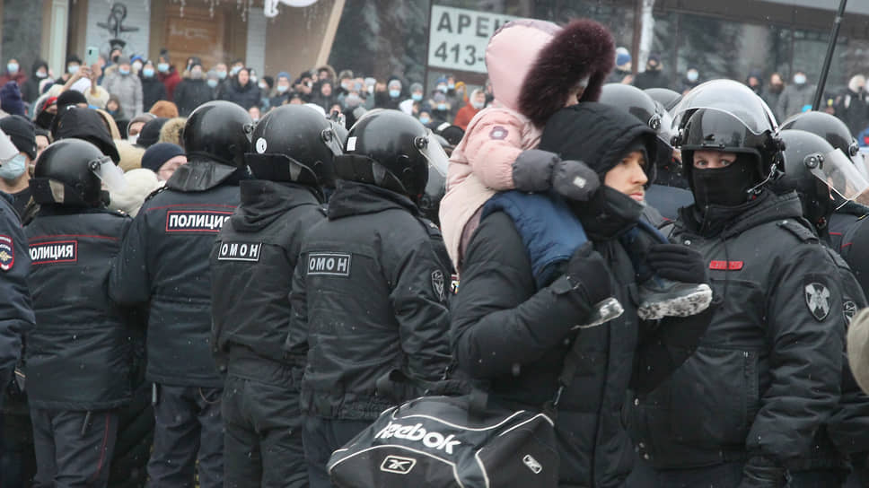 23 января. Мужчина с ребенком на плечах идет мимо цепи ОМОНа во время митинга протеста в поддержку оппозиционера Алексея Навального на центральной пешеходной улице Нижнего Новгорода Большой Покровской
