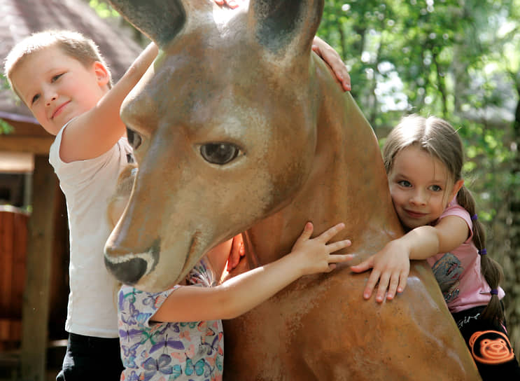 Дети на скульптуре кенгуру в зоопарке