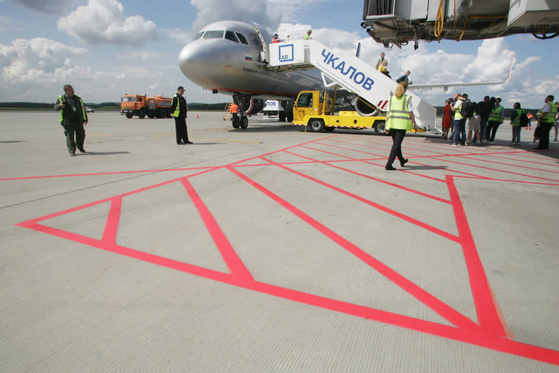 Аэродромная служащая идет по таможенной разметке к самолету Airbus