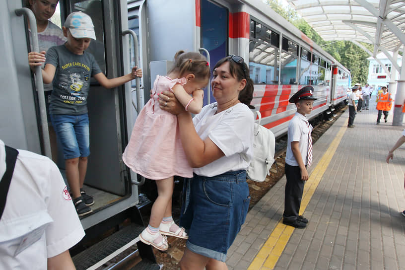 Женщина высаживает детей из вагона после поездки