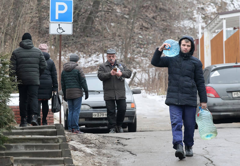 Мужчина несет бутыли, заполненные крещенской водой из источника