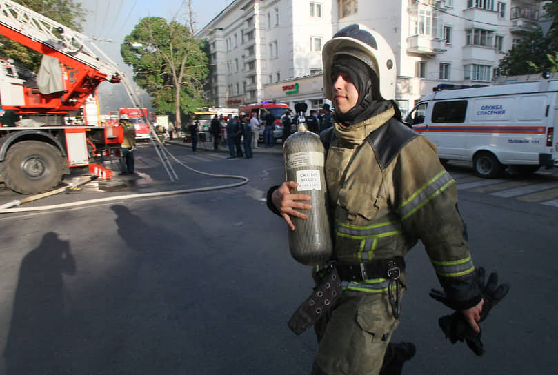 Пожарный несет баллон с кислородом во время ликвидации возгорания