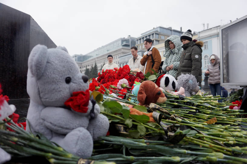 Цветы и детские игрушки на постаменте памятника Чкалову