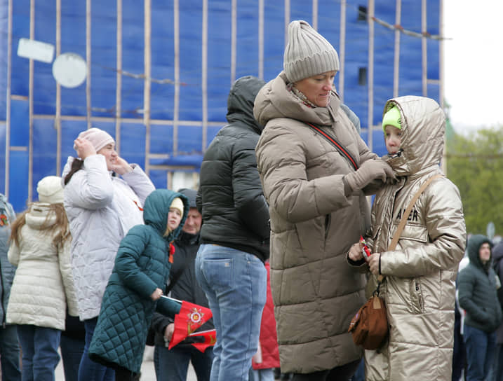 Женщина укутывает дочь у ограждения