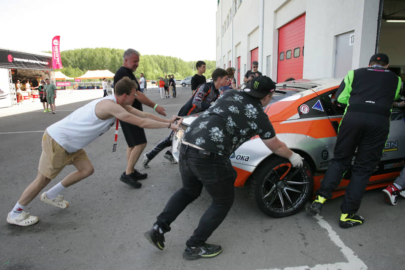 Члены команды закатывают автомобиль в бокс
