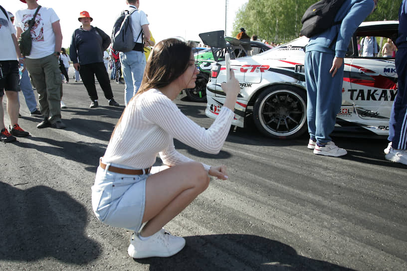 Девушка фотографирует автомобили гонщиков