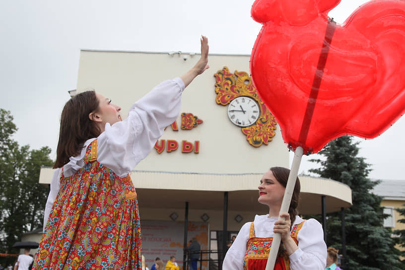  Девушка в русском народном сарафане тянется к воздушному шару, имитирующему леденец на палочке