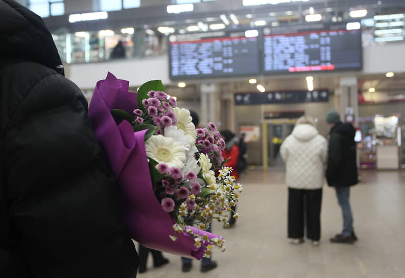 Мужчина с букетом ожидает прибытия поезда