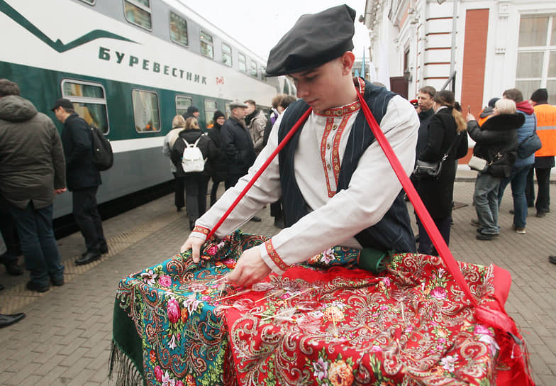 Аниматор в народном костюме раздает леденцы