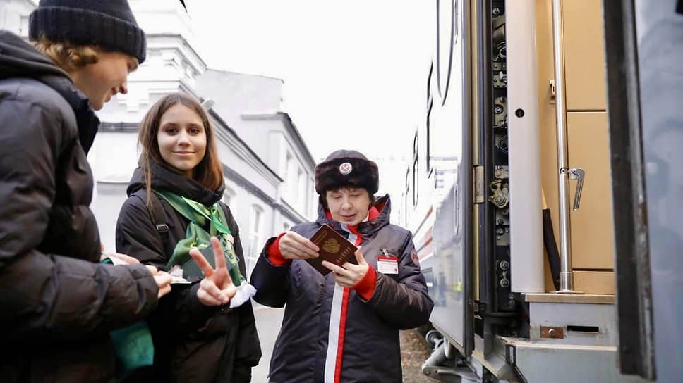 Проводница проверяет документы у пассажиров туристического поезда ГЖД