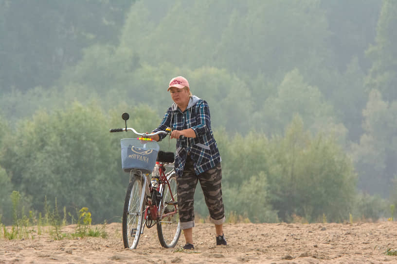 Женщина с велосипедом на фоне новосибирской дымки