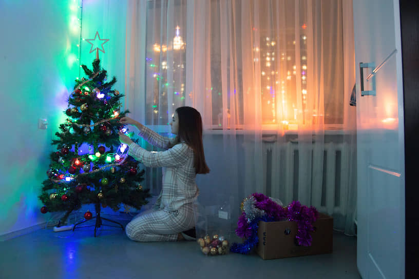 Жительница Новосибирска наряжает искусственную елку в своей квартире