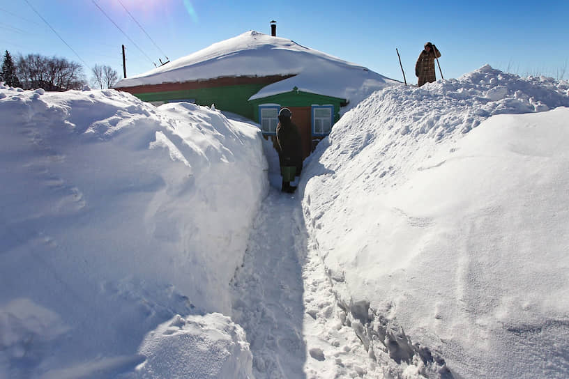 Последствия снегопадов в селе Барановка Змеиногорского района Алтайского края. Жительницы села чистят тропинку к дому