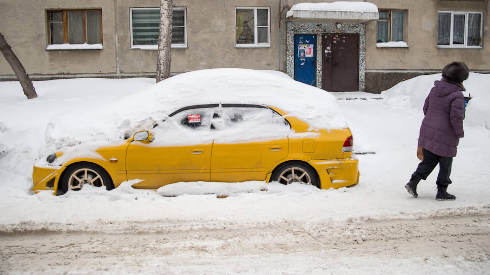 Занесенный снегом автомобиль во дворе дома в центре города