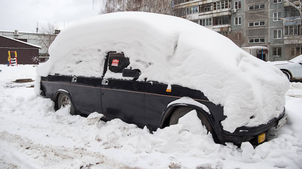 Занесенный снегом автомобиль во дворе дома
