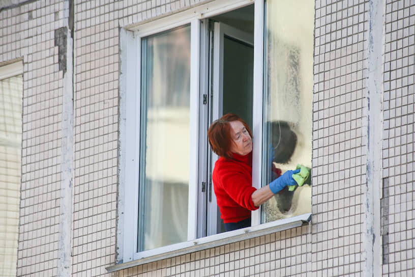 Пожилая женщина моет окна в своей квартире. Сибиряки стали намного больше заботиться о чистоте своего жилища. 