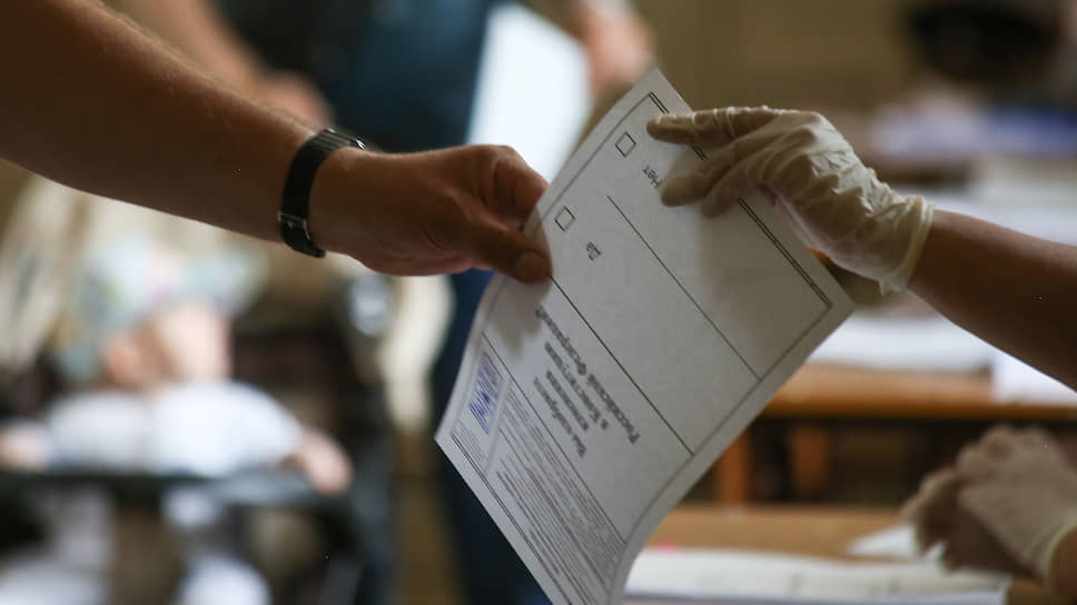 Член избирательной комиссии передает в руки избирателю бюллетень для голосования