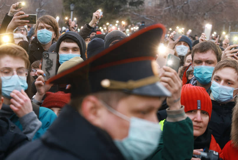 Несанкционированный митинг в поддержку оппозиционера Алексея Навального. Сотрудник полиции и участники акции с включенными фонариками на мобильных телефонах