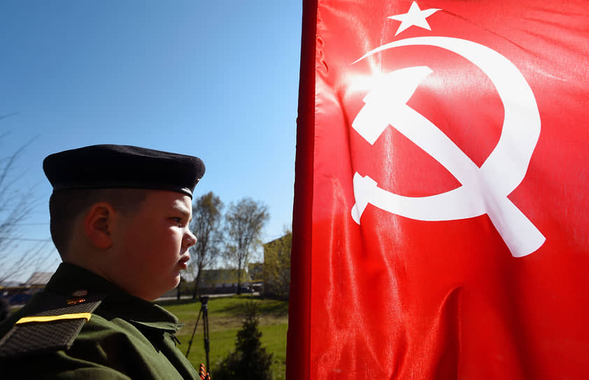 Празднование Дня Победы в поселке Евсино Искитимского района. Юноша в военной форме у Флага СССР