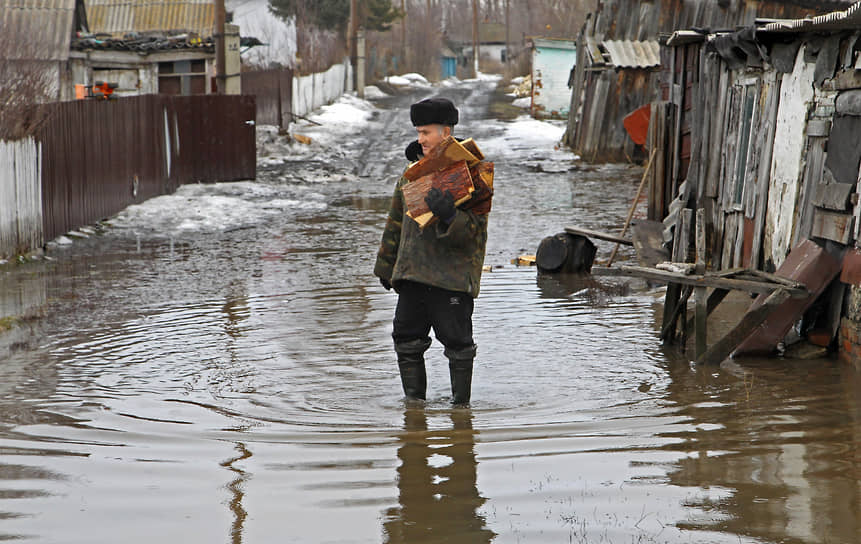 Затопленный от таяния снега частный сектор Барнаула (Алтайский  край). Мужчина с охапкой дров 