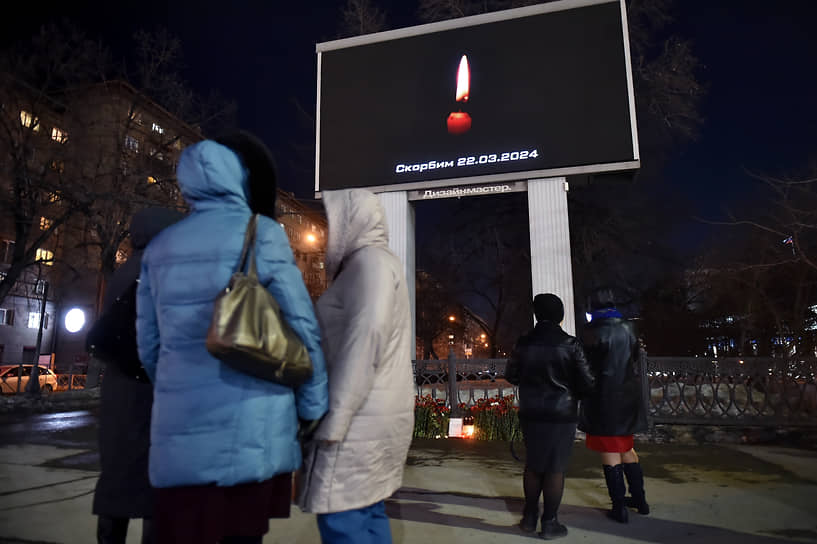 Акция памяти жертв теракта в подмосковном концертном зале «Крокус Сити Холл» в Новосибирске. Люди у стихийного мемориала рядом с баннером с изображением свечи и надписью «Скорбим. 22.03.2024»