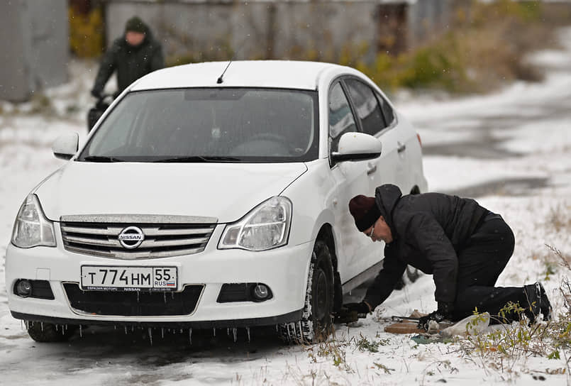 Первый снег в Омске. Мужчина очищает автомобиль от снега