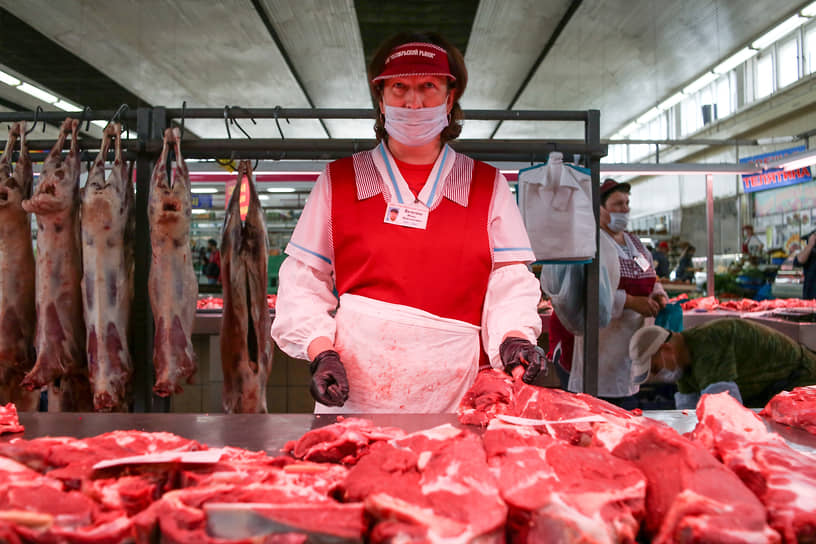 Продавщица мяса в медицинской маске за прилавком на Октябрьском рынке Новосибирска