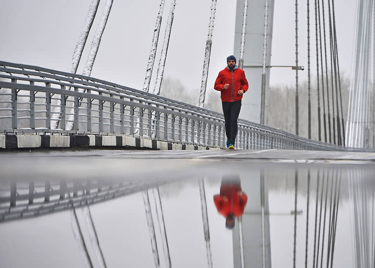 Мужчина во время утренней пробежки на пешеходном мосту острова Татышев в Красноярске