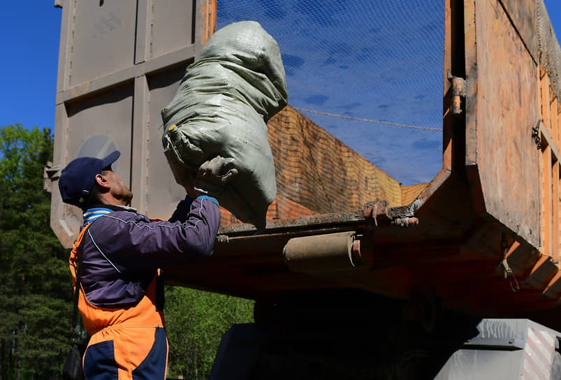 Сотрудник компании по вывозу мусора во время погрузки мусора в грузовик