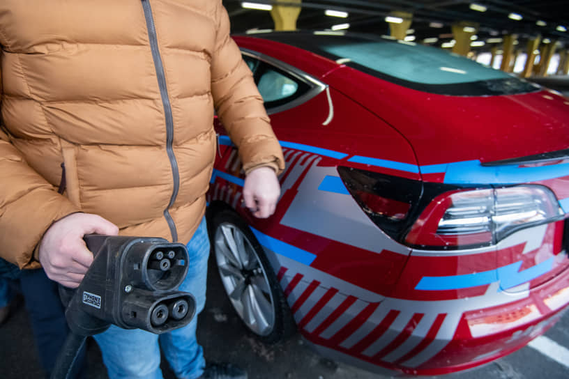 Водитель подключает автомобиль к электрозарядной станции