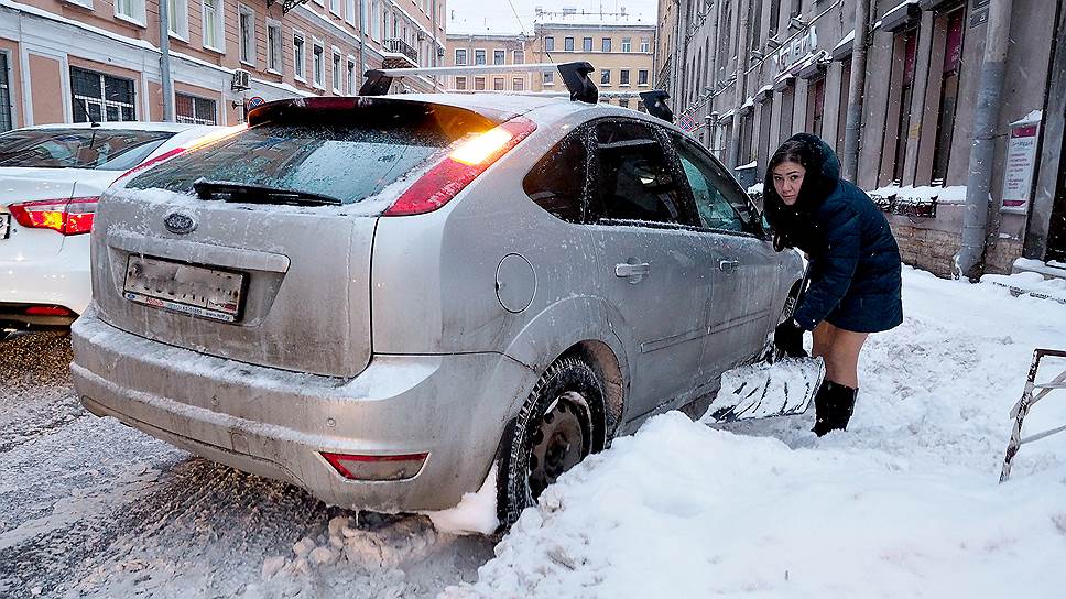 Девушка откапывает свой автомобиль из снежного заноса на Гончарной улице