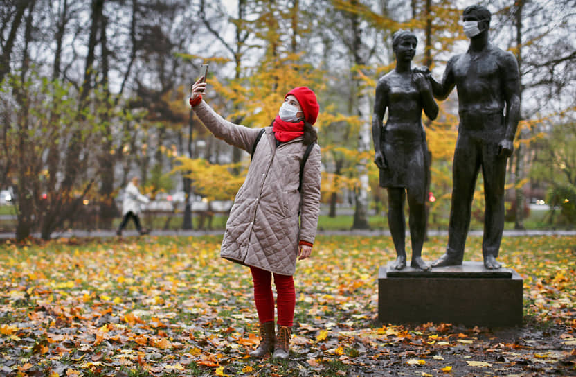 Девушка в медицинской маске фотографируется на фоне скульптуры &quot;Молодость&quot; в Александровском парке