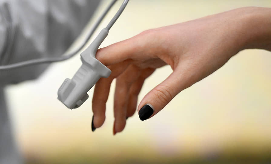 Рука девушки с прибором для измерения сатурации (уровень кислорода в крови)