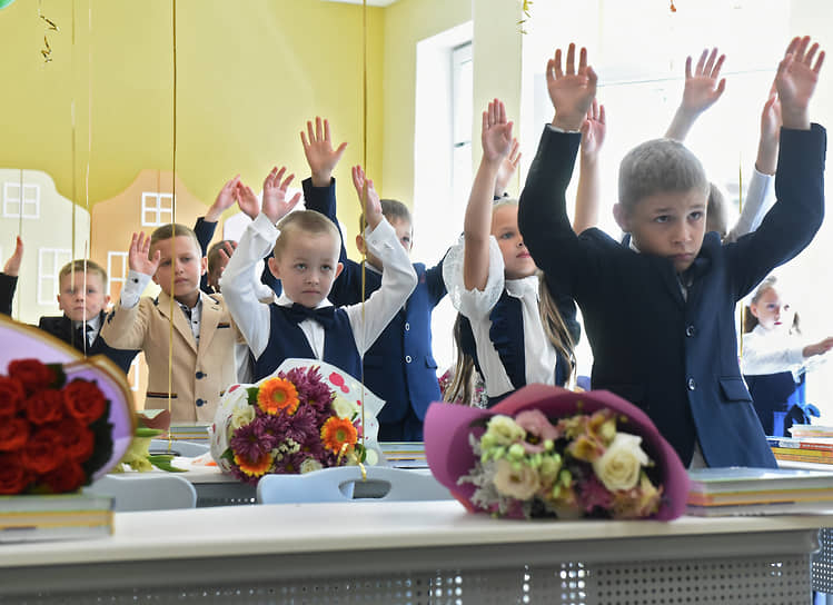 1 сентября, День знаний. Первоклассники под руководством учителя делают физические упражнения во время урока в классе новой среднеобразовательной школе № 478