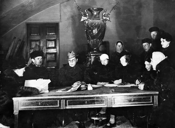 1942 год. Слушают доклад главного хранителя ГРМ М. В. Фармаковского. Слева направо сидят: М. В. Фармаковский, Ю. Н. Дмитриев, и. о. директора ГРМ Г. Е. Лебедев, М. Г. Фракман, В. В. Алексеева, В. Е. Фармаковская, М. Г. Слонимская. Стоят: В. С. Макеева — комендант здания, В. С. Дреммог, В. Г. Демидюк, В. Г. Панова
