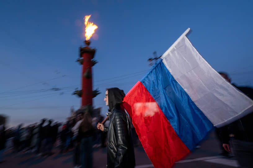 Молодой человек с флагом Российской Федерации перед салютом в ознаменование 80-й годовщины победы в Великой Отечественной войне