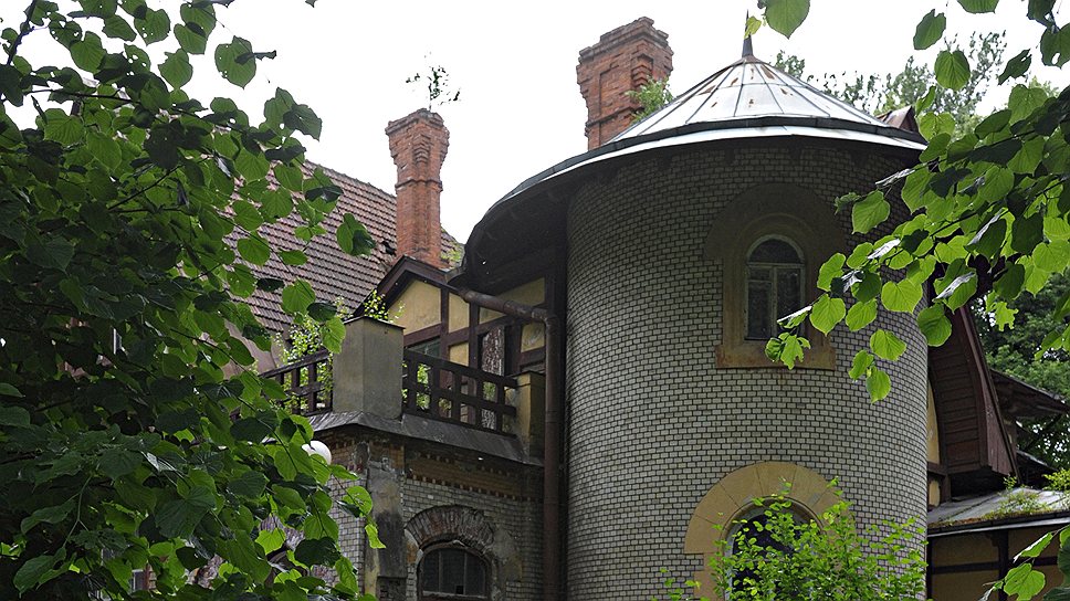 Угловая полукруглая каменная башенка с полуциркульными окнами делает этот дом похожим на маленький замок