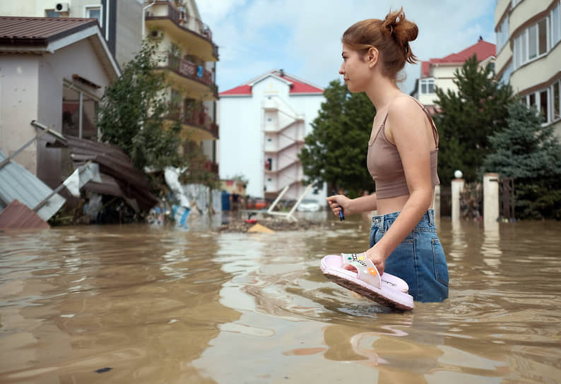 Июль 2021 г. Россия, Краснодарский край, Туапсинский р-он
Последствия наводнения в Лермонтове. Затопленная водой проезжая часть. Девушка туристка идет по пояс в воде на фоне гостиниц.