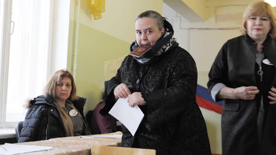 Женщина с паспортом во рту готовится проголосовать. Март, 2018 год
