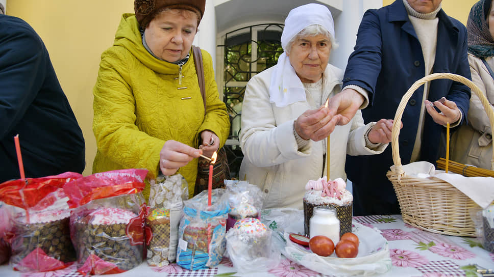 Люди зажигают свечи на пасхальных куличах