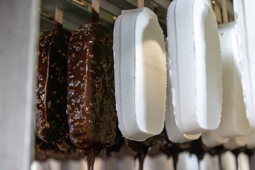 Перед упаковкой часть мороженого (например, эскимо) погружают в теплую шоколадную глазурь, с орехами или без. Разница температур позволяет глазури мгновенно застыть на поверхности, сохранив нежную текстуру внутри. На фото: мороженое перед и после покрытия шоколадной глазурью