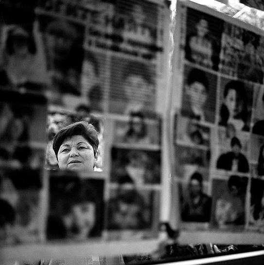  Женщина смотрит на портреты пропавших без вести. Человек с вынутой фотографии найден, но неизвестно, живым или мёртвым
