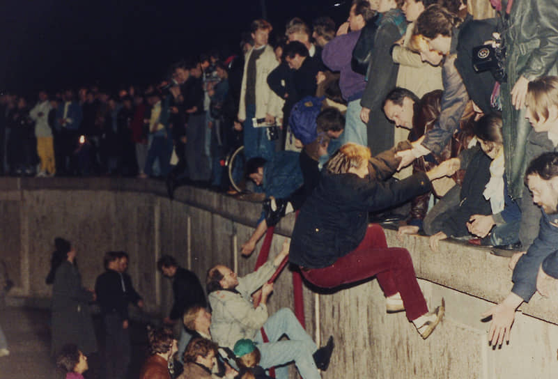 Жители обеих частей Берлина у Берлинской стены в районе Бранденбургских ворот в ночь с 9 на 10 ноября 1989
