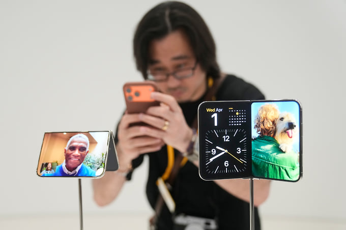 Посетитель мероприятия фотографирует главную новинку Apple iPhone Duo 