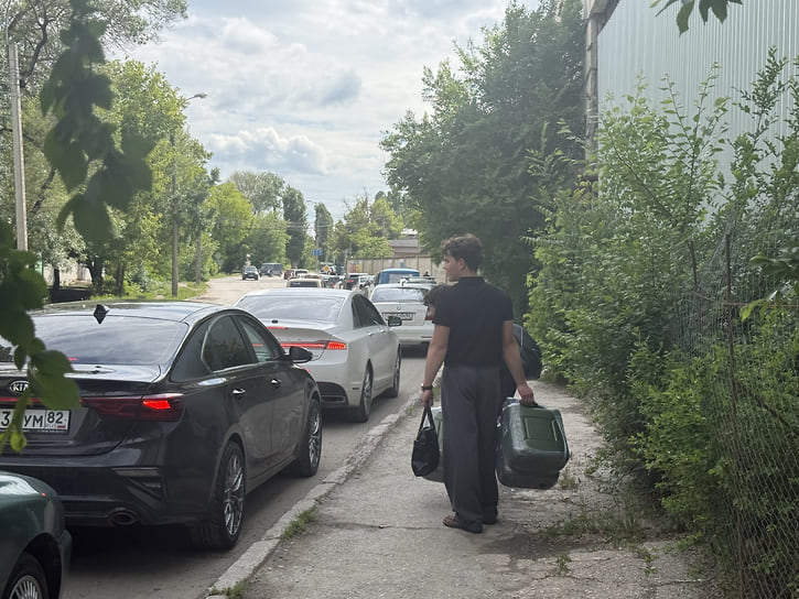 Люди, стоящие в конце очереди, подходят ближе, чтобы выяснить, хватит ли им бензина 
