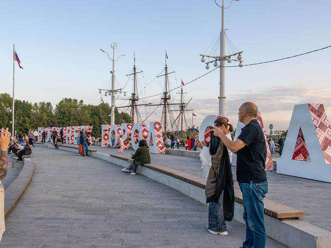 Гости отдыхают у стеллы «Город-сад» в финале первого дня фестиваля в 2025 году