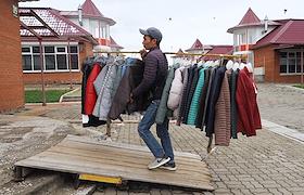 Окончание рабочего дня на вещевом рынке. Продавцы из Вьетнама и других азиатских стран убирают товар - одежду