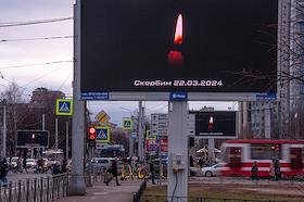 Светодиодный уличный экран с горящей свечой и надписью 'Скорбим 22.03.2024' и 'Петербург скорбит 22.03.2024', в память о жертвах теракта в подмосковном концертном зале 'Крокус Сити Холл'